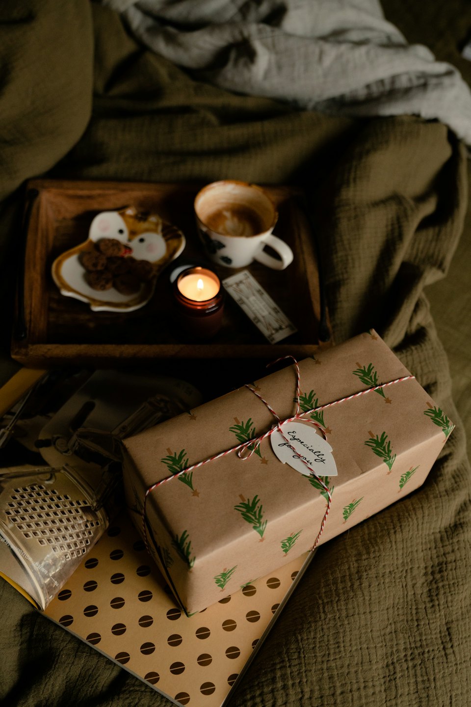Wrapped gift and coffee on a bed with cookies.