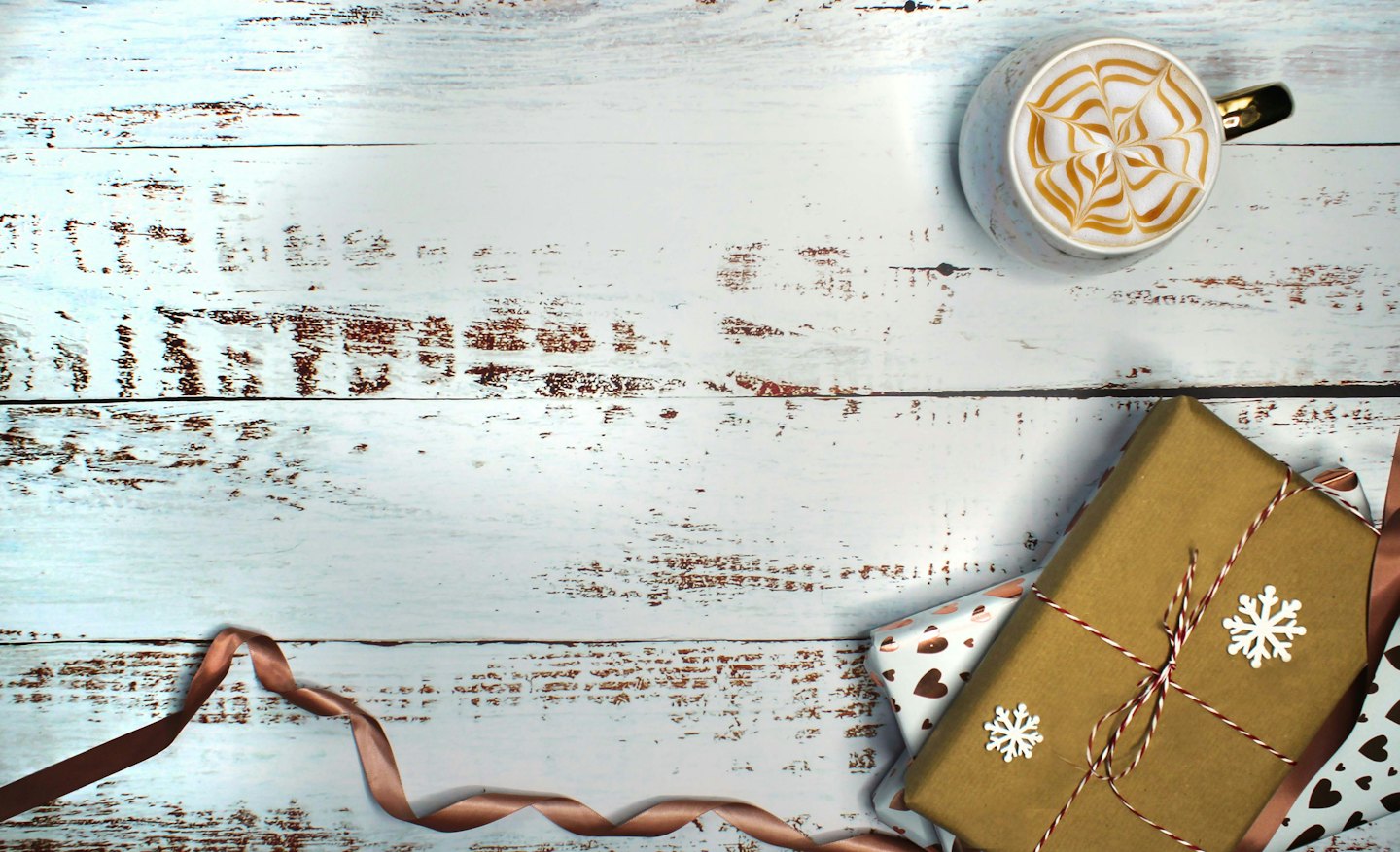 Two wrapped gifts and a coffee sit on a wooden table.